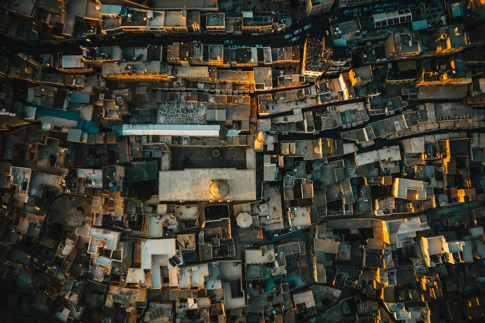 Drone shot over Mardin, Turkey, showcasing historic stone architecture under warm sunlight.